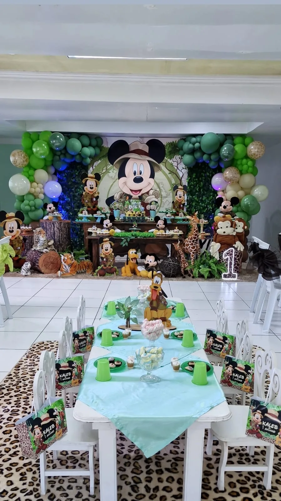 Decoração tema Mickey Safari no Salão Superior com painel verde, animais selvagens e mesa de doces